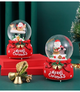 Detail of red resin Christmas snow globes featuring Santa Claus scenes and gold bells