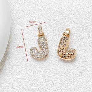 Detailed view of gold letter J pendant with cubic zirconia and 16mm by 30mm dimensions