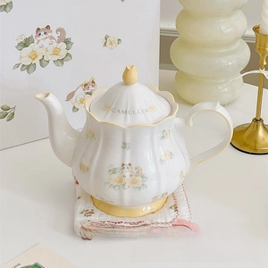 Detail of ceramic teapot featuring yellow camellia and cat prints with a floral knob