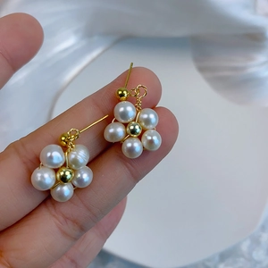 Macro shot of a flower-shaped earring featuring five white pearls and a golden center stud