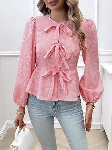 Detail of pink and white plaid blouse featuring lantern sleeves and triple bow accents