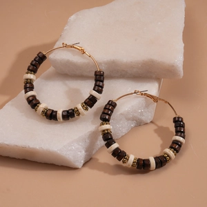 Detailed shot of bohemian hoop earrings with dark wood beads and gold metal accents