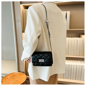 Quilted black chain crossbody bag worn by a model in a professional office setting