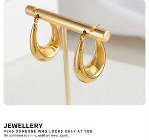 Detailed close-up of polished gold-plated U-shaped drop earrings on a jewelry stand