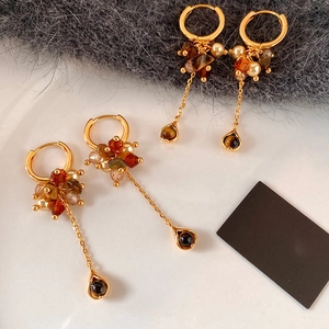 Macro view of vintage earrings with tiger eye beads and pearls on a white ceramic plate