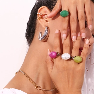 Close-up of model wearing chunky rings with irregular gemstones and golden jewelry