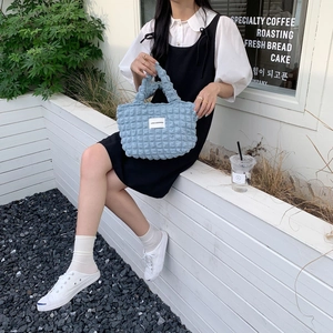 Detail of light blue bubble texture canvas handbag with white brand label and handles