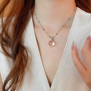 Detail of a sparkling amber crystal round pendant on a silver beaded chain necklace