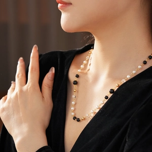 Détail d'un collier double couche avec perles, billes noires et touches dorées sur modèle