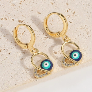 Détail macro de boucles d'oreilles cœur œil maléfique en or avec émail bleu et cristaux