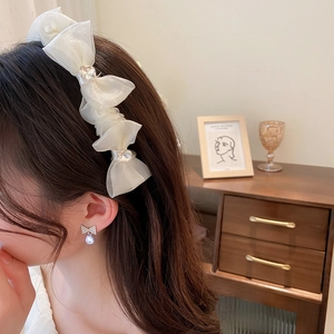Close-up of white mesh bow headband with crystal beads and matching droplet earrings