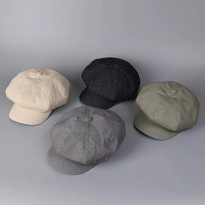 Top view of corduroy newsboy caps in ivory, black, grey, and green showing texture
