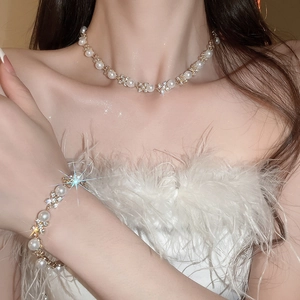 Dettaglio del set di collana e bracciale con fiori e perle indossato da una modella