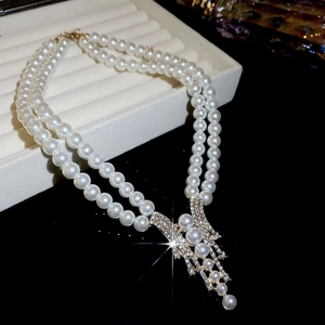 Detail of a double-layer pearl necklace with a gold tassel pendant in a jewelry box
