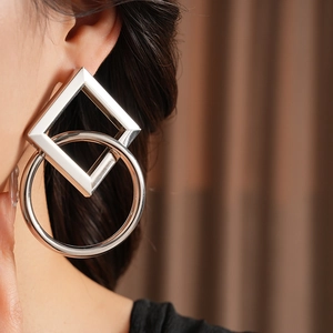 Gros plan de boucles d'oreilles argentées géométriques avec anneaux carrés et ronds