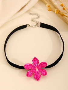 Macro view of a large pink hollow flower choker with a black suede band and lobster clasp
