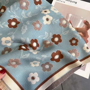 Detailed close-up of light blue scarf showing soft knitted floral texture and patterns