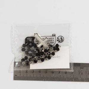 Detail of gothic cross necklace with black beads measured with a ruler for size reference