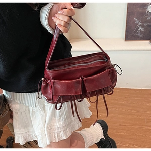 Detail of dark red bowling bag with pleated drawstring pockets and glossy leather finish