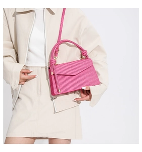 Detail of pink woven texture handbag with knotted handle and golden metal buckles
