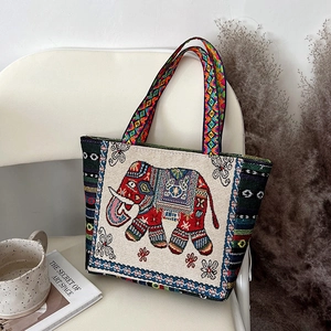 Detail of red elephant embroidery and colorful ethnic handle on beige canvas tote bag