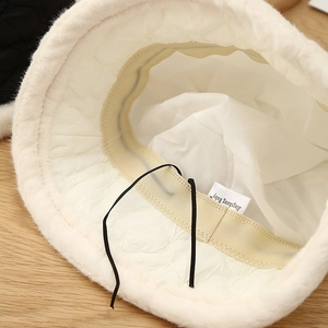 Detail view of white plush bucket hat featuring quilted lining and adjustable drawstring