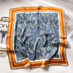 Detailed close-up of retro paisley silk scarf texture on a white surface and fashion magazine
