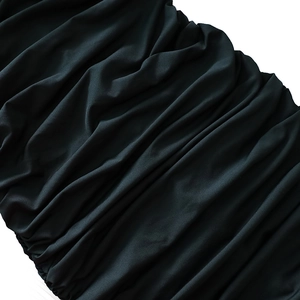 Detail of dark green ruched fabric showing elegant pleated texture and soft glossy finish