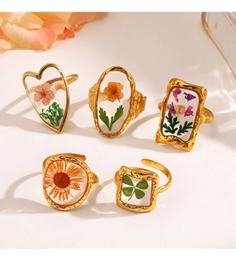 Detailed close-up of five gold stainless steel rings with real flowers in clear resin