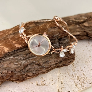 Detailed view of rose gold quartz bracelet watch with butterfly accents and stone charms