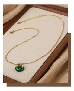 Detailed shot of green malachite pendant with gold-plated bead chain on silk