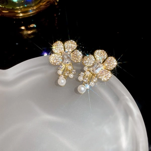 Detail of floral pearl earrings with zircon stones and elegant gold setting in macro view