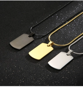 Polished stainless steel ID tags in black, gold, and silver on a dark background