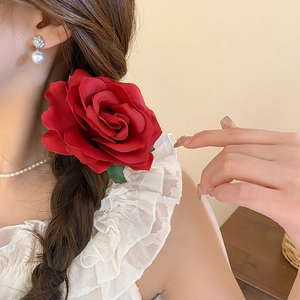 Detailed view of a vibrant red fabric rose hair clip worn on a braided hairstyle