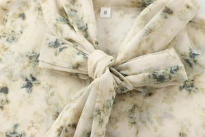Détail de chemisier en mousseline fleurie avec col à nœud et motif rétro chic