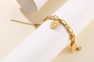 Detail of double-layer gold chain bracelet with sun and moon embossed coin pendants