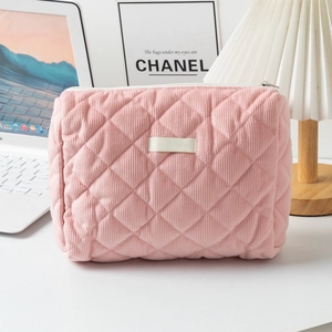 Détail d'une trousse à maquillage en velours côtelé rose avec motif à losanges matelassés