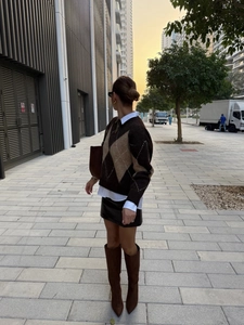 Street style view of a brown diamond pattern knit sweater with leather mini skirt and boots