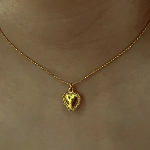 Gros plan d'un collier pendentif cœur doré avec chaîne à boules porté au cou
