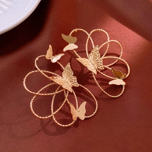 Macro shot of gold twist-texture flower earrings with butterfly relief details