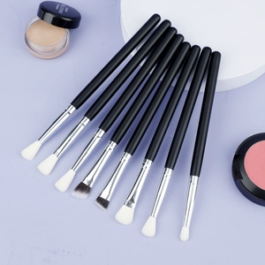 Flat lay of 8-piece eye makeup brush set with matte black handles on a purple background