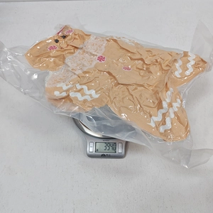 Gingerbread man plush pillow on scale showing 394g weight in transparent packaging