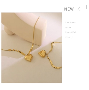 Close-up of gold heart pendant and cube bead details on delicate snake chain jewelry