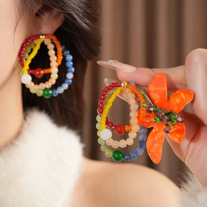 Detail view of colorful beaded hoop earrings with a large orange flower accent