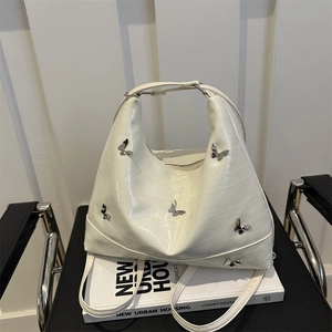 Borsa tote bianca trama anguilla con farfalle d'argento su sedia nera elegante