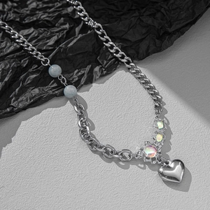 Chic silver-tone patchwork necklace with heart pendant and blue beads on black paper