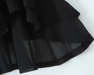 Detail view of the layered black mesh hem and ruffled edge on a long chiffon dress