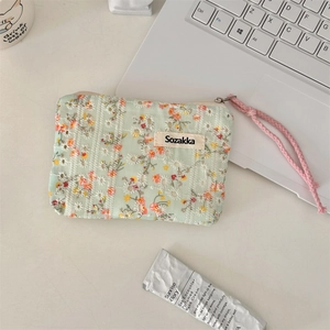 Close-up of floral mint green canvas pouch with pink drawstring on a white desk