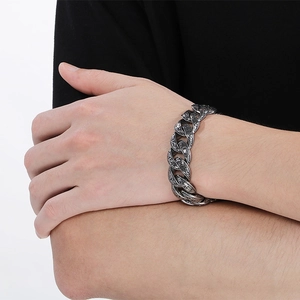 Close-up of vintage engraved silver Cuban link bracelet on wrist for punk style