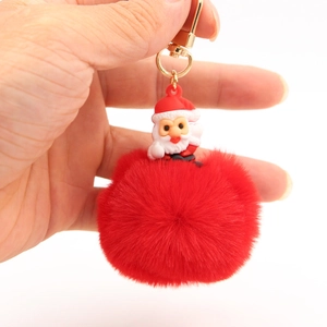 Detail of red pompom keychain with Santa Claus figurine and gold metal hardware